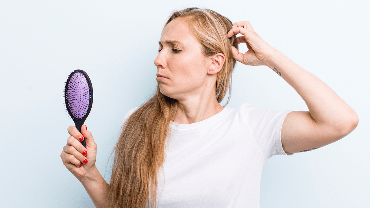 vrouw met haaruitval kijkt bedroefd in de spiegel